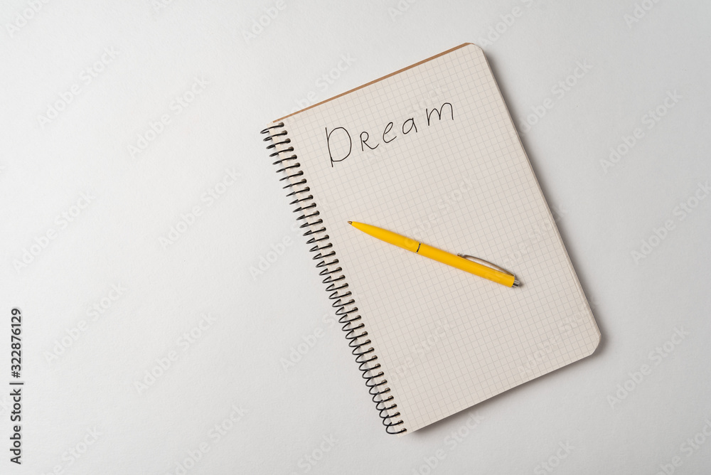 Handwritten word Dream. Inscription in notebook on white background. Top view Handwritten word Dream. Inscription in notebook on white background. Top view