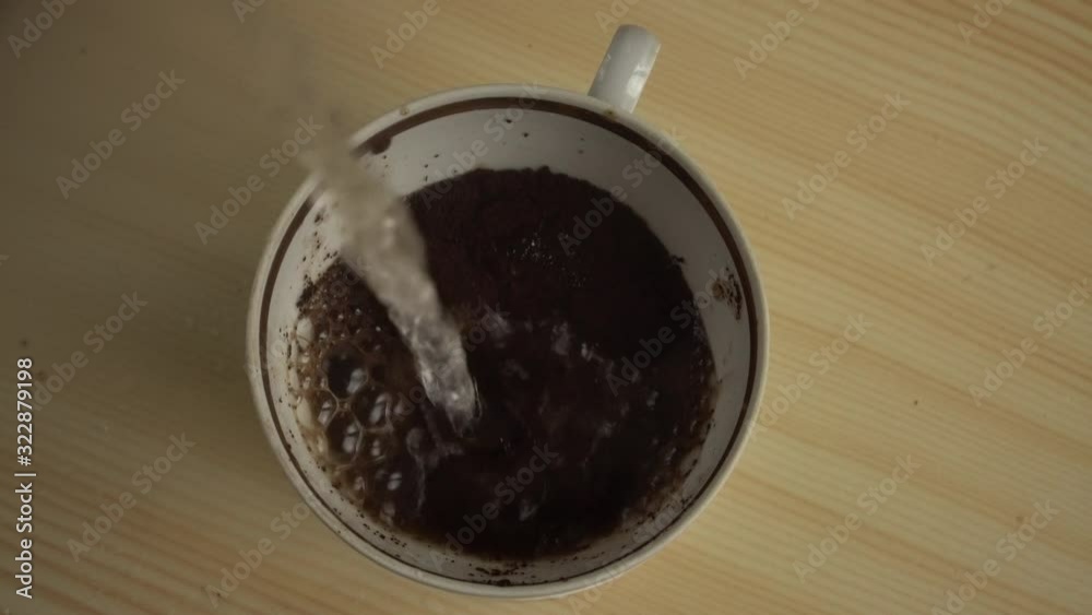 A crazy coffee making ritual. Things are not going as they should. A cup on a table is filled with ground coffee and pouring boiling water with splashes. A crazy coffee making ritual. Things are not going as they should. A cup on a table is filled with ground coffee and pouring boiling water with splashes.