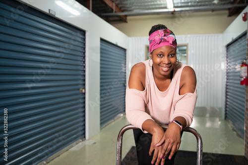 Portrait of a woman leaning over a cart inside a storage facility., Jacksonville, Florida, USA photo