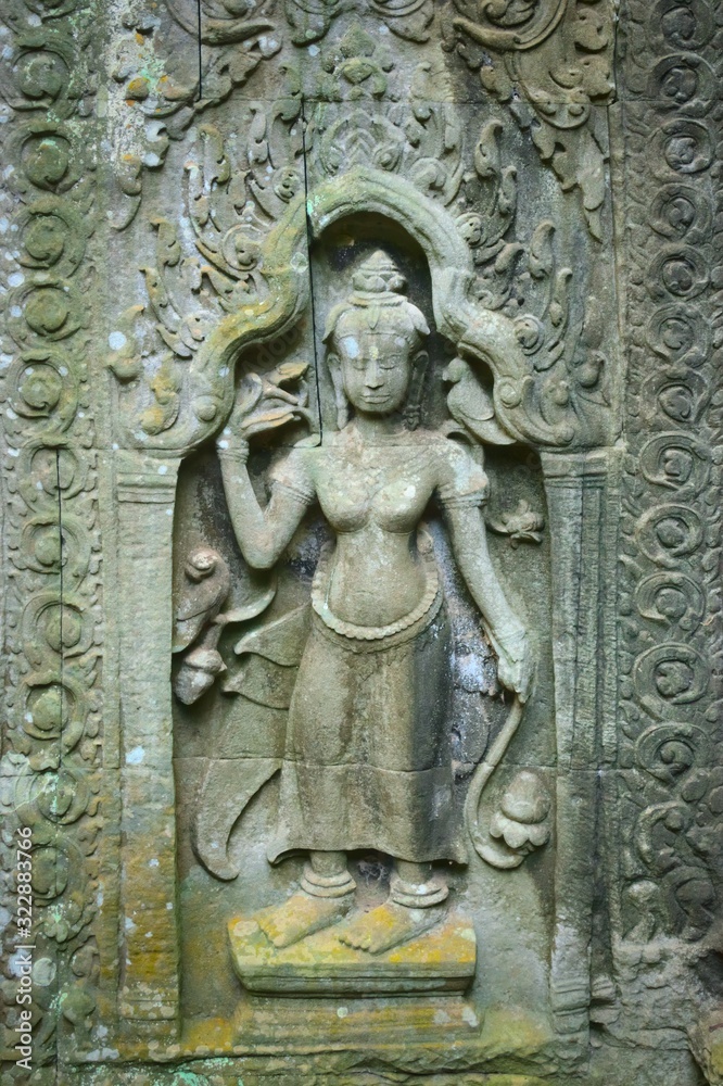 Apsara in bas-relief on a wall at Ta Prohm temple ruins, located in Angkor Wat complex near Siem Reap, Cambodia.