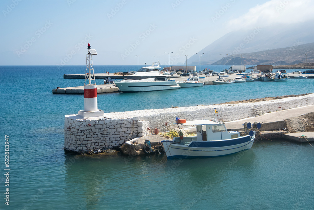 The old harbor at the charming, small Greek island of Kasos.  Small fishing boats and pleasure craft  docked in the bay on a summers day.  The blue sky provides copy space.