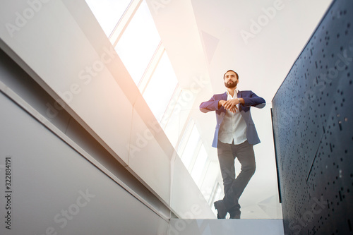 Successful handsome businessman in a blue suit at the workplace looks out the window  portrait of a manager at work