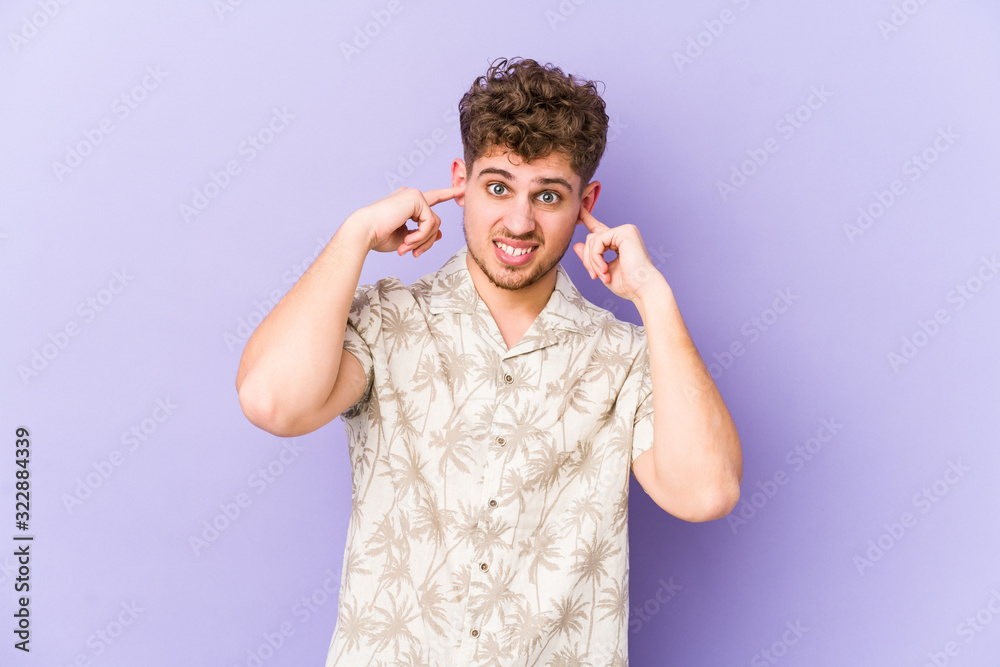 Young blond curly hair caucasian man isolated covering ears with fingers, stressed and desperate by a loudly ambient. Young blond curly hair caucasian man isolated covering ears with fingers, stressed and desperate by a loudly ambient.