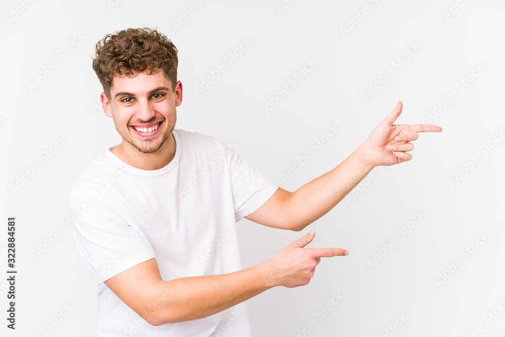 Young blond curly hair caucasian man isolated excited pointing with forefingers away. Young blond curly hair caucasian man isolated excited pointing with forefingers away.