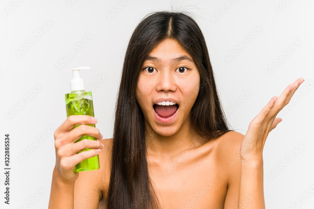 Young chinese woman holding a moisturizer with aloe vera isolated celebrating a victory or success Young chinese woman holding a moisturizer with aloe vera isolated celebrating a victory or success