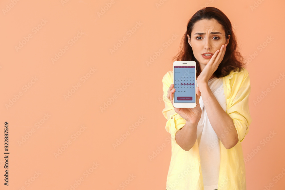 Young woman with menstrual calendar on mobile phone screen against color background Young woman with menstrual calendar on mobile phone screen against color background