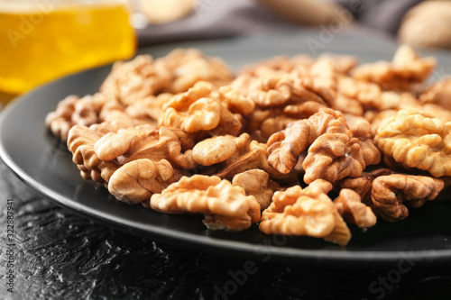 Plate with tasty walnuts on table, closeup