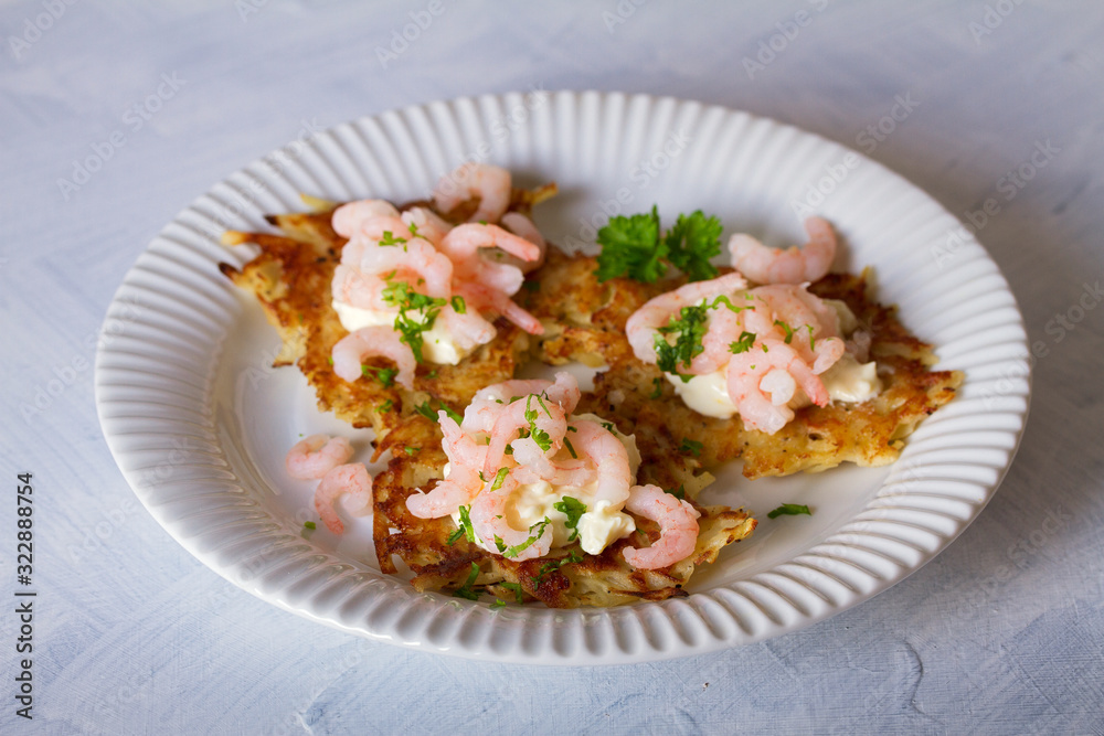 Potato cakes with topping: cream cheese and shrimps on white plate. Vegetable fritters, pancakes. Horizontal image Potato cakes with topping: cream cheese and shrimps on white plate. Vegetable fritters, pancakes. Horizontal image