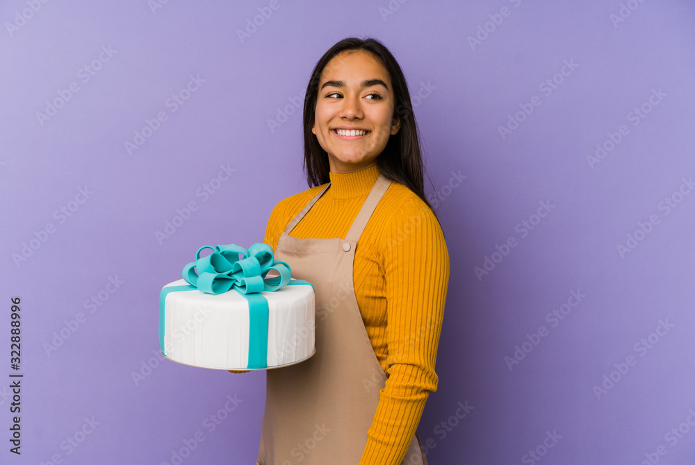 Young asian woman holding a cake isolated looks aside smiling, cheerful and pleasant. Young asian woman holding a cake isolated looks aside smiling, cheerful and pleasant.