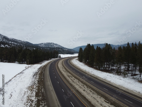 Two curving roadways cutting through a snow covered valley with tall trees
