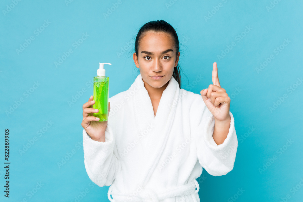 Young mixed race indian holding an aloe vera bottle showing number one with finger. Young mixed race indian holding an aloe vera bottle showing number one with finger.