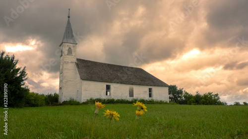 Old Church in grassy field with clouds in background