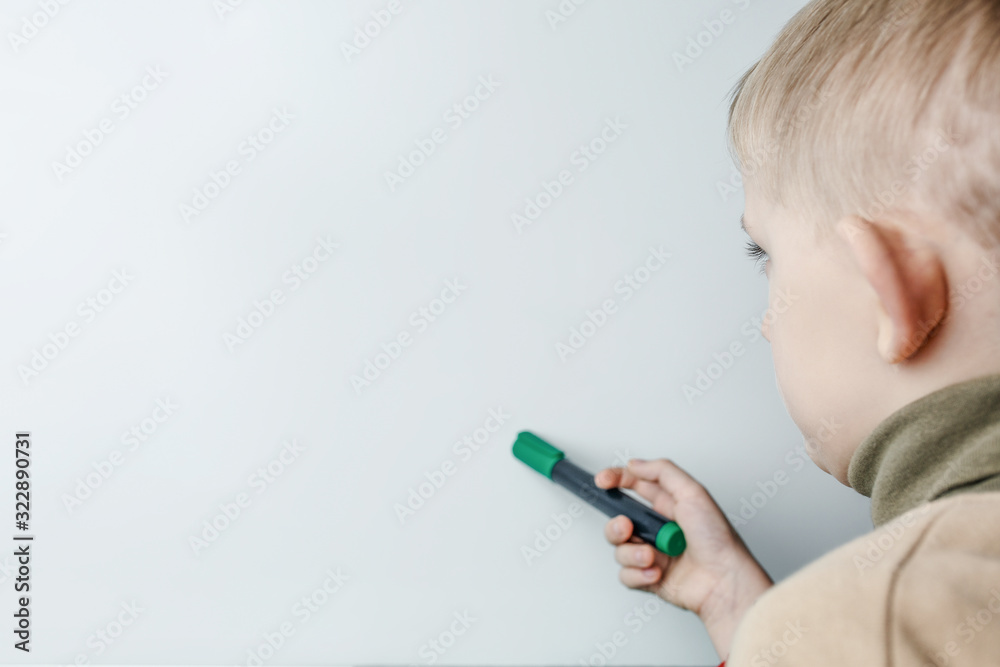 child with a marker in his hand thinks over a task child with a marker in his hand thinks over a task