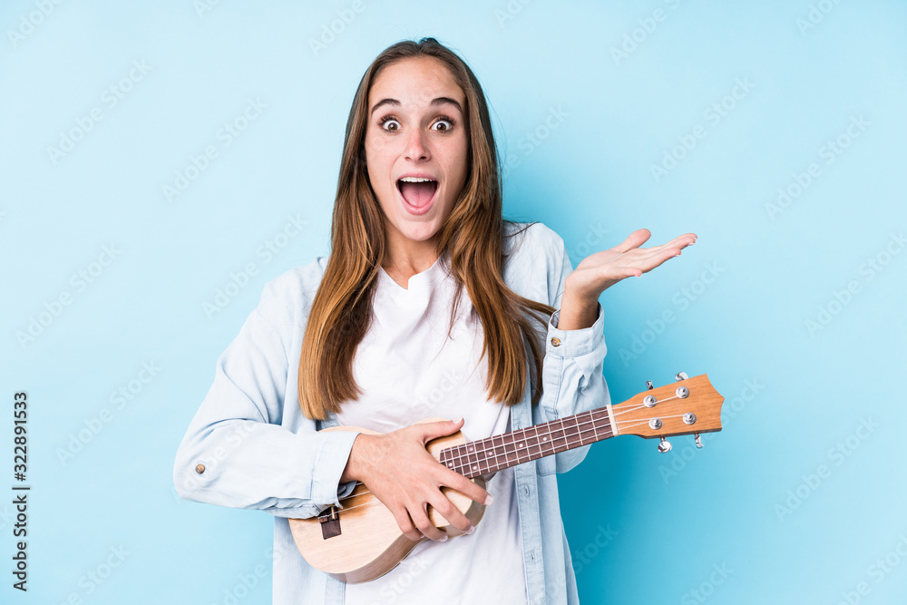Young caucasian woman holding a ukelele isolated celebrating a victory or success Young caucasian woman holding a ukelele isolated celebrating a victory or success