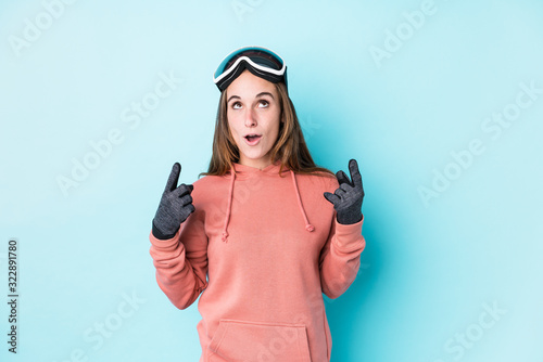 Young skier woman isolated pointing upside with opened mouth. © Asier