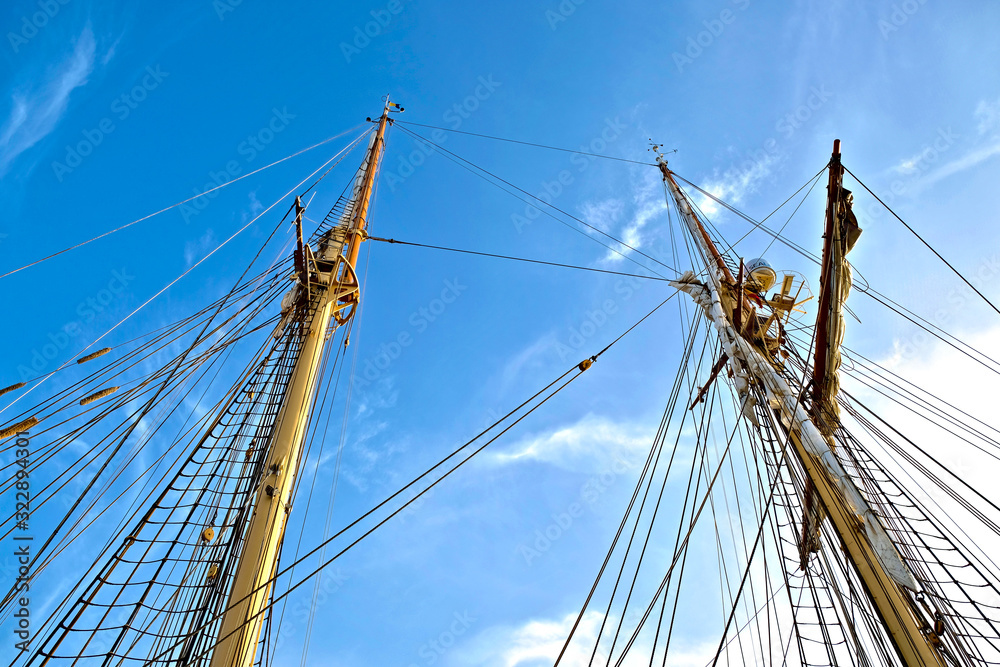 Tall masts and rigging of a classic sailing ship. Blue skye in the background. Tall masts and rigging of a classic sailing ship. Blue skye in the background.