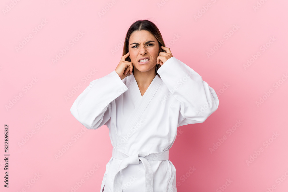 Young karate woman covering ears with hands. Young karate woman covering ears with hands.