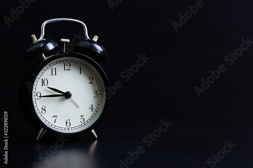Old black vintage alarm clock in dark black background