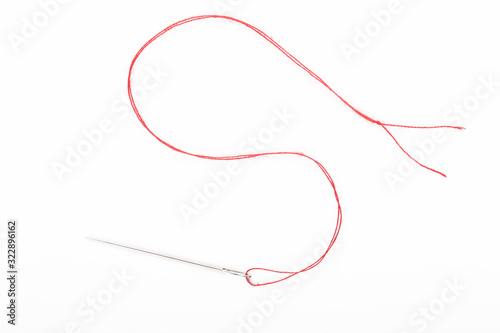 Fotografia, Obraz Sewing needle with red thread on the white background