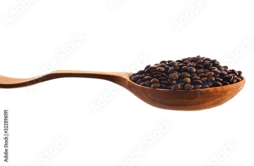 Brown lentils in the wooden spoon isolated on a white background.