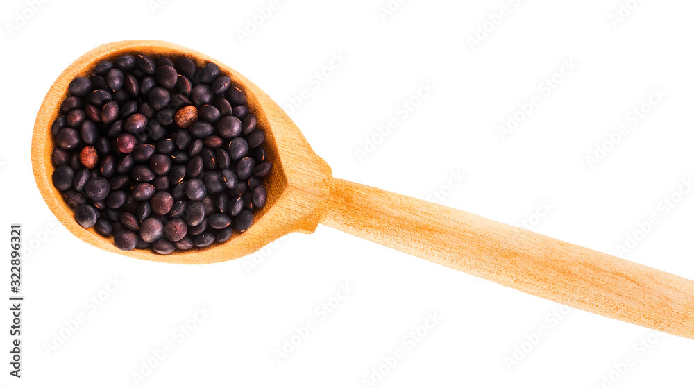 Black lentils in the wooden spoon isolated on a white background. Top view. Black lentils in the wooden spoon isolated on a white background. Top view.