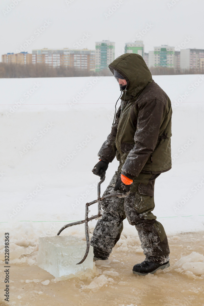 Naklejka premium Fitter with steel tongs pulls out ice block