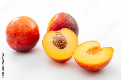 Vitamins source and healthy eating concept with group of whole raw nectarines and one half juicy nectarine with the pit exposed isolated on white background