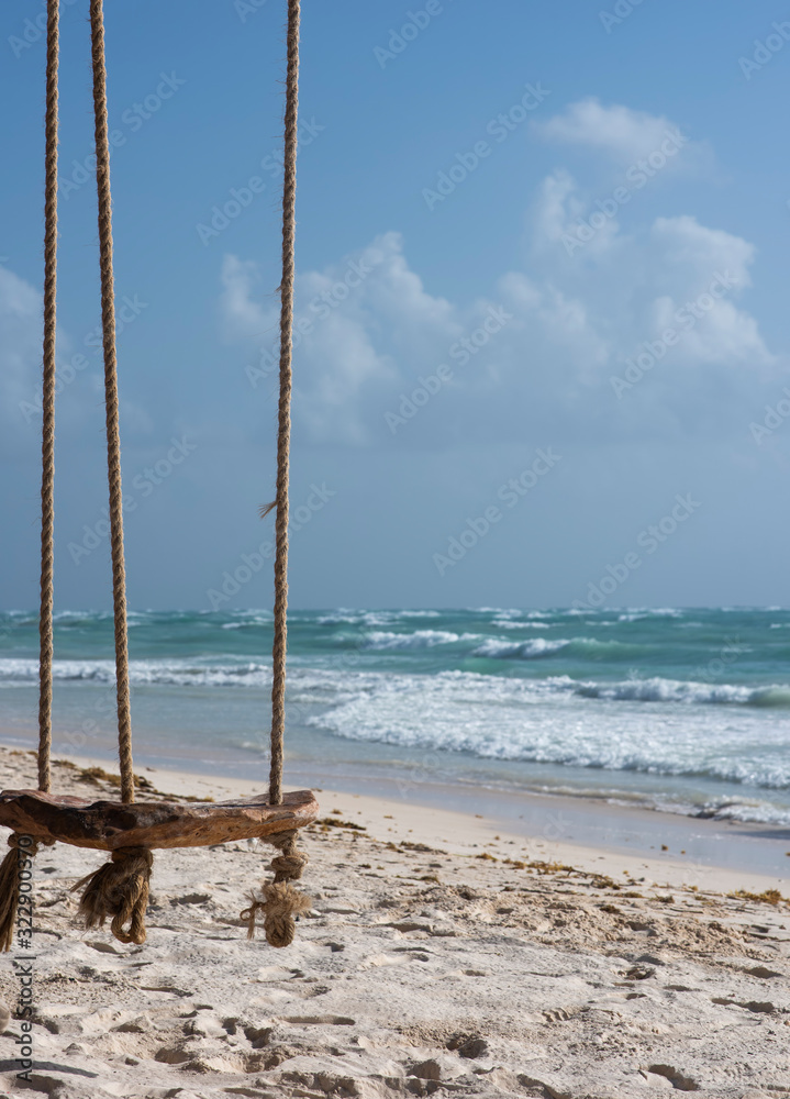 Close-up suspended chair on the beach at Tulum Mexico. Caribbean ocean and cloud sky background