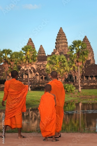 Wallpaper Mural Three young monks at Angkor Wat, in traditional saffron colored robes, admiring the majestic temple. Torontodigital.ca