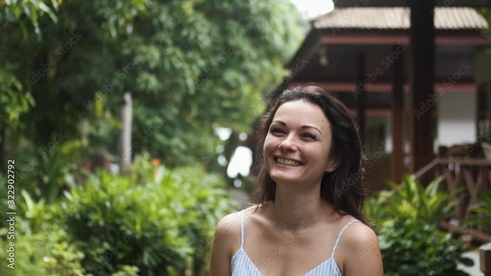 Portrait of an attractive brunette girl of European appearance, she is looking at the camera and smiling on a summer sunny day with light rain Portrait of an attractive brunette girl of European appearance, she is looking at the camera and smiling on a summer sunny day with light rain
