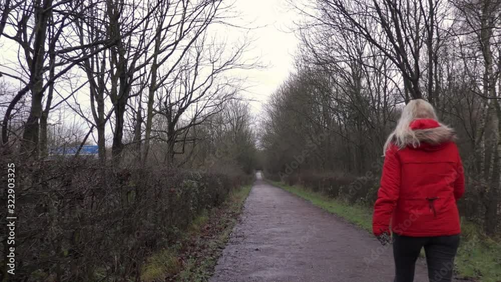 Blonde girl in red coat walking in a forest Blonde girl in red coat walking in a forest