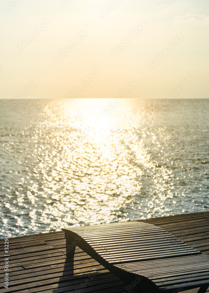 Beautiful sunset with wooden lounge chair and sea
