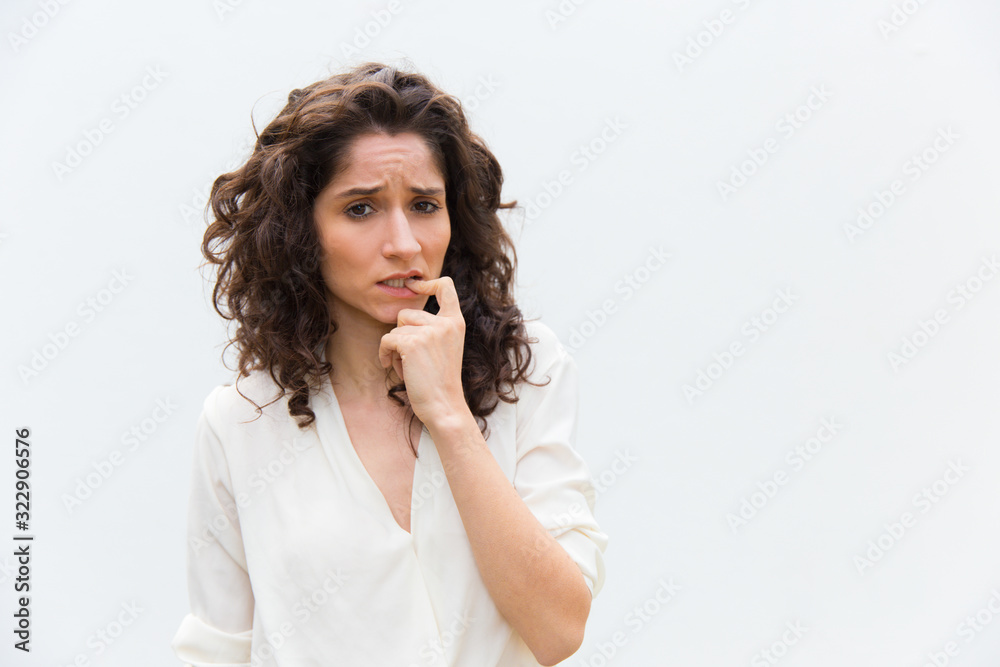 Thoughtful young woman biting finger. Worried female thinking something while posing in studio. Searching decision, stress concept Thoughtful young woman biting finger. Worried female thinking something while posing in studio. Searching decision, stress concept