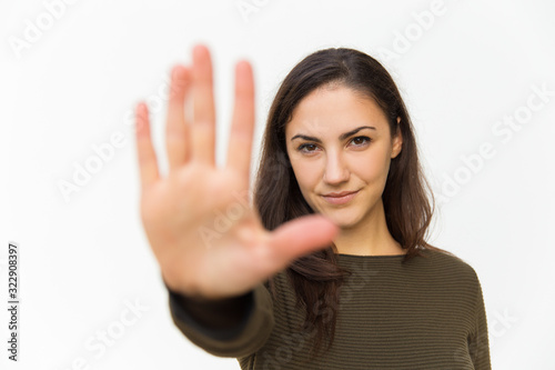 Serious young woman showing stop gesture. Beautiful lady with outstretched arm. Warning or prohibition concept