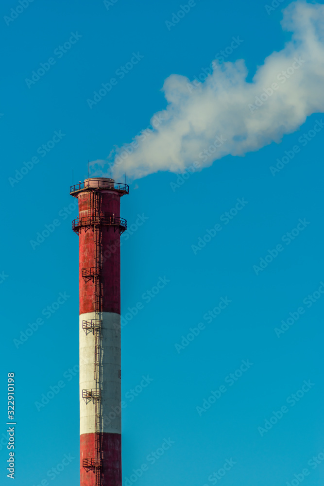 Vertical image of an industrial chimney with white smoke causing air pollution Vertical image of an industrial chimney with white smoke causing air pollution