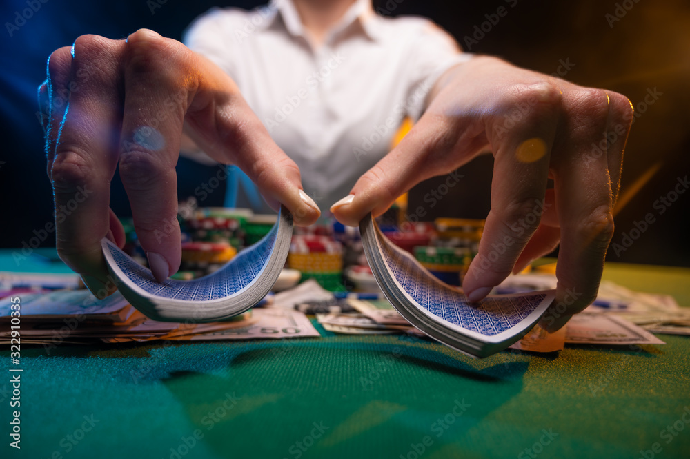 Φωτογραφία Girl dealer or croupier shuffles poker cards in a casino on the background of a table, chips,