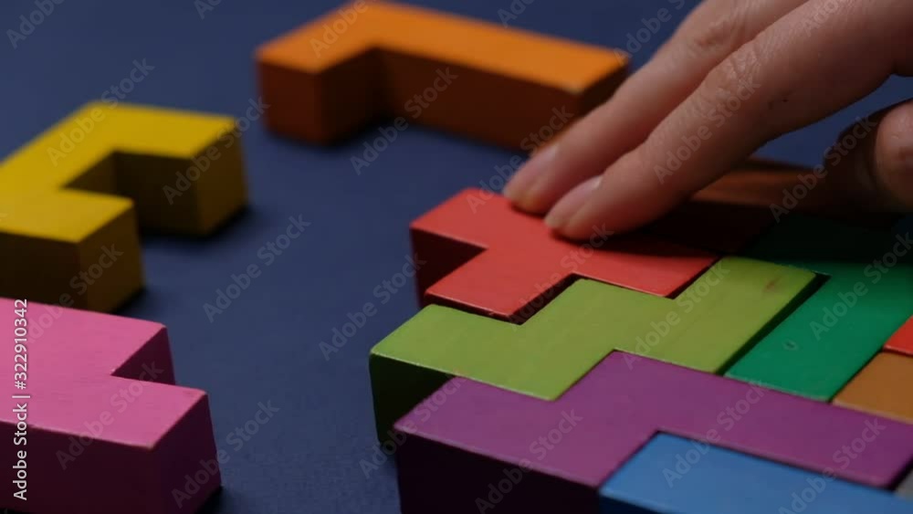 Closeup Slow motion. Hand holding piece of wooden block puzzle. wood cube stacking. Concept of complex and smart logical thinking. on a black background