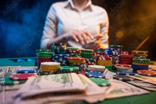 Girl dealer or croupier shuffles poker cards in a casino on the background of a table  chips . Concept of poker game  game business
