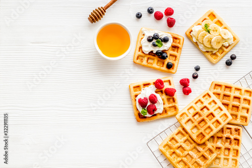 Beautiful yummy snacks. Waffles with cream and friuits on white background top-down frame copy space