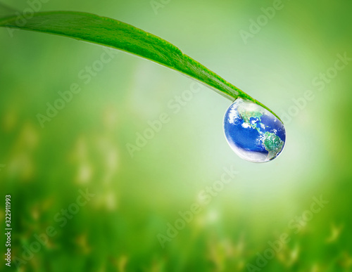 Earth in water drop under green leaf on natural green grass blur background, Earth day, Water and environment concept, Elements of this image furnished by NASA
