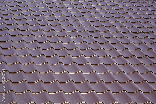 Close up of brown steel roof. Dark steel tiled roof background, Europe. View of a new house. Construction of a new residential private house on blue sky background.