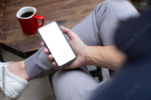 Mockup image blank white screen cell phone.man hand holding texting using mobile on desk at coffee shop.background empty space for advertise text.people contact marketing business,technology © panitan