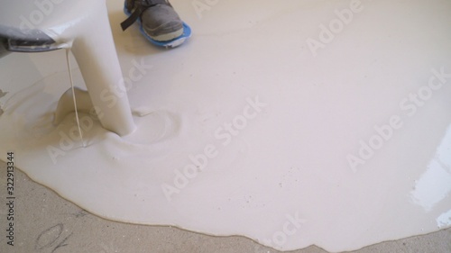 Interior of apartment under construction. Mirror smooth surface of the floor. Floor covering with self leveling cement mortar. Roller application. Floor repair. Self-filling floors photo