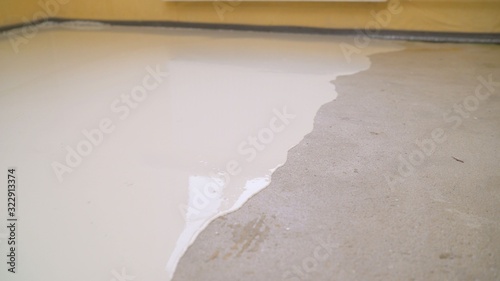 Interior of apartment under construction. Mirror smooth surface of the floor. Floor covering with self leveling cement mortar. Roller application. Floor repair. Self-filling floors