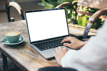mockup image blank screen computer with white background for advertising text,hand woman using laptop contact business search information on desk at coffee shop.marketing and creative design