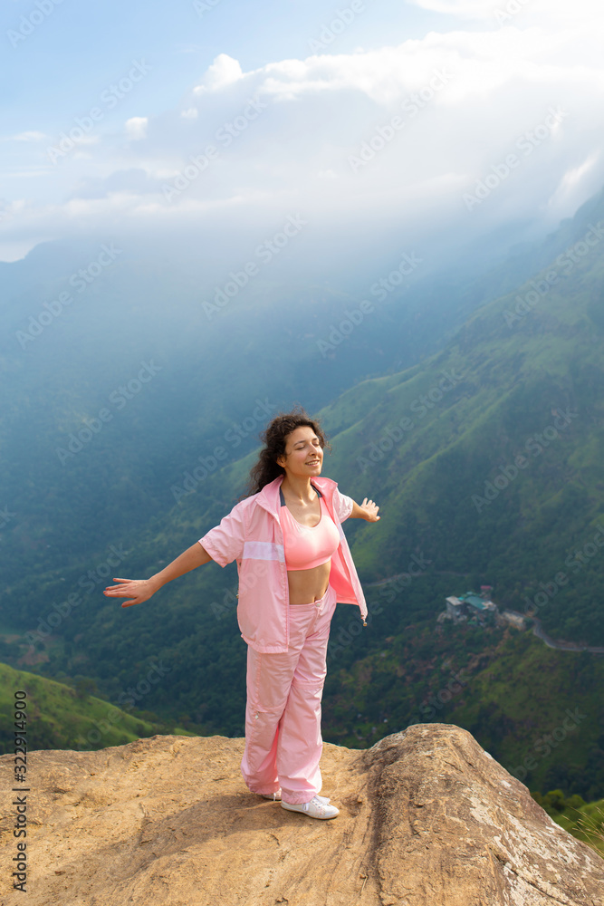 Naklejka premium Girl enjoys a mountain view while standing on a cliff