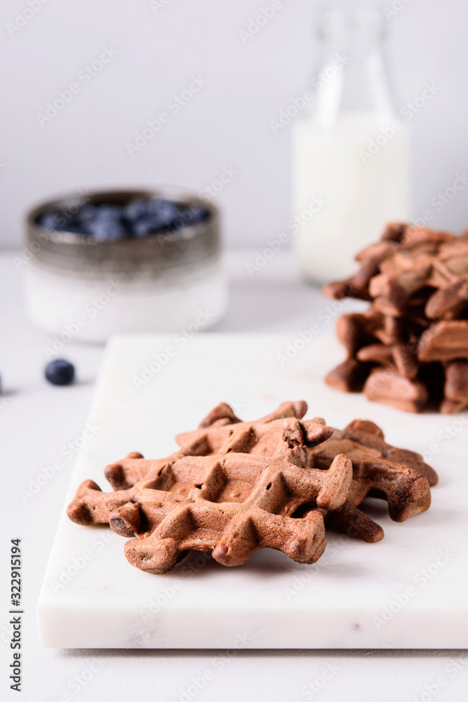 Homemade Chocolate waffles, milk and blueberries on white marble tray. Breakfast. Selective focus