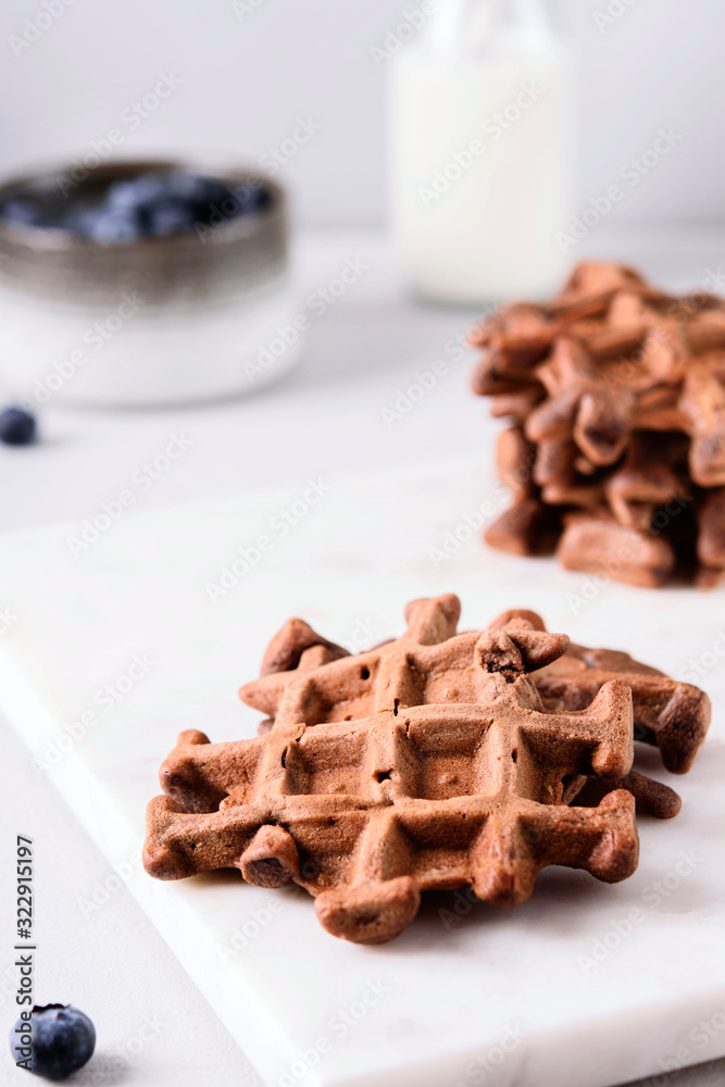 Homemade Chocolate waffles, milk and blueberries on white marble tray. Breakfast. Selective focus Homemade Chocolate waffles, milk and blueberries on white marble tray. Breakfast. Selective focus