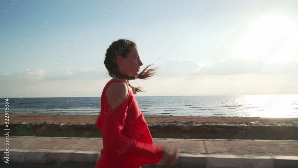 Athletic woman jogging on the promenade by the ocean at sunrise slow motion Athletic woman jogging on the promenade by the ocean at sunrise slow motion