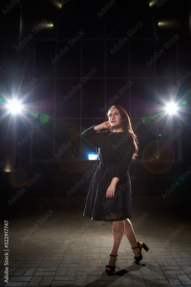 Portrait of chubby teen girl near wall of building outdoors and color flashes in the dark and black background Portrait of chubby teen girl near wall of building outdoors and color flashes in the dark and black background